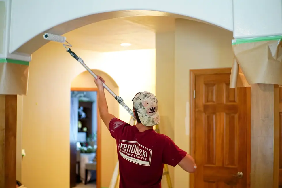 A painter in a Kenowski Painting shirt rolling fresh paint around an arched opening
