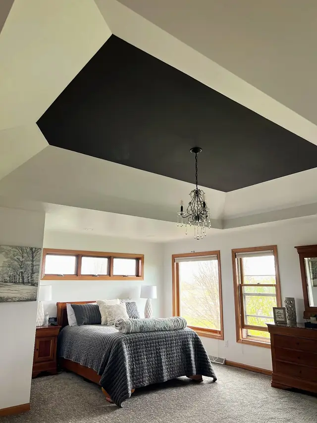 A primary bedroom with a black tray ceiling over light walls