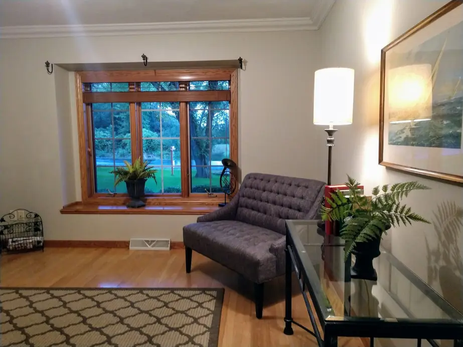 A living room with a lake-view window and warm wood, freshly painted by Kenowski