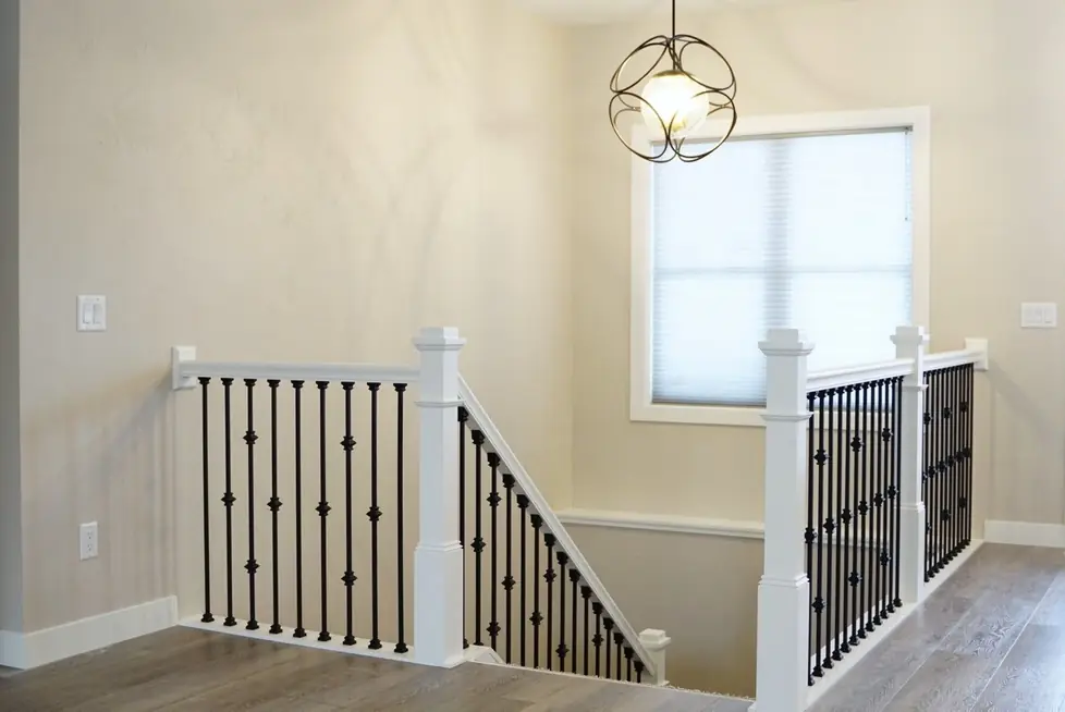 A white spindle staircase with cream walls and a smooth, freshly painted finish