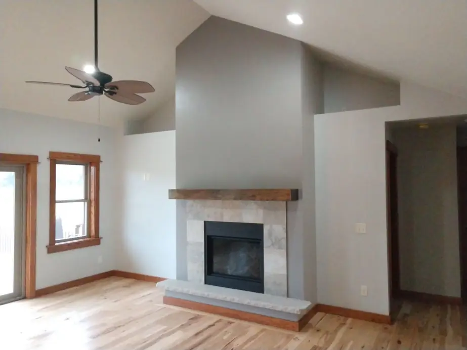 A vaulted great room with fresh gray walls and a stone fireplace
