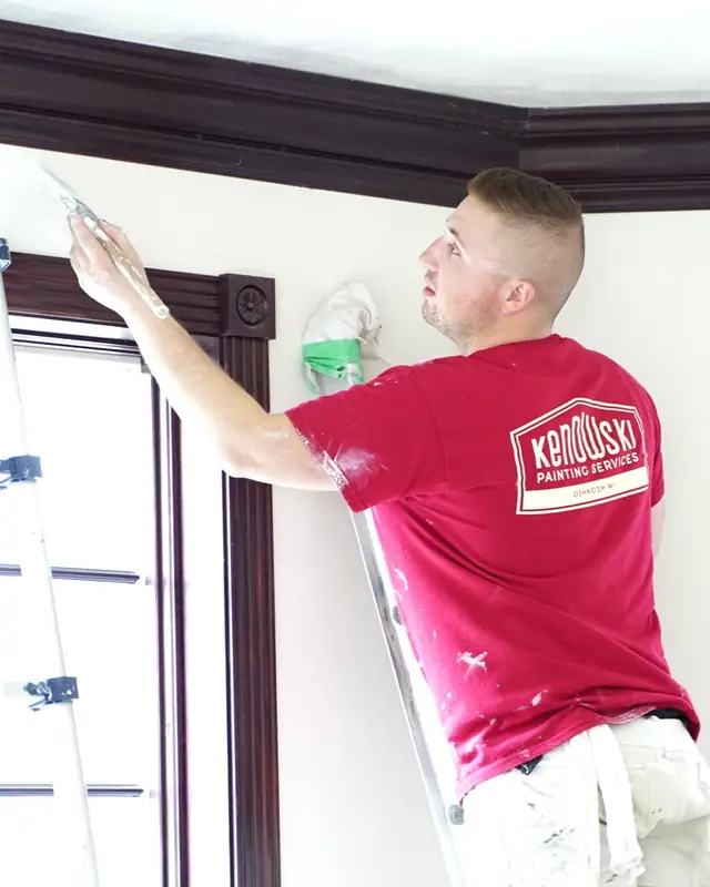A Kenowski painter cutting in along crown trim, company logo on the shirt